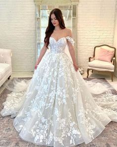 a woman in a white wedding dress standing on a carpeted floor with her hands behind her back