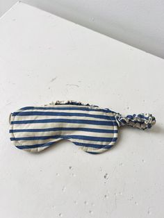 a blue and white striped eye mask laying on top of a table