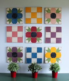 four potted plants sitting on top of a green table next to wooden squares with flowers painted on them