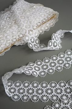 two pieces of white crochet lace next to each other on a gray surface