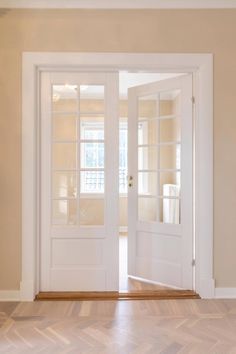 an empty room with two white doors and wood flooring on either side of the door