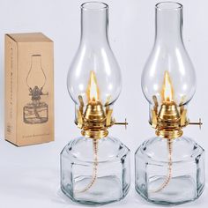 two clear glass lamps sitting next to each other on a white surface with a box in the background