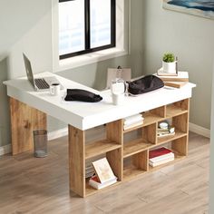 a white desk with books and a laptop on it in front of a large window