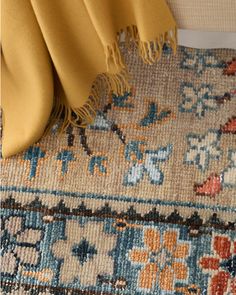 a yellow blanket is laying on top of a blue and beige rug with an orange border