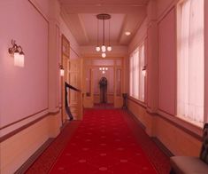 an empty hallway with red carpet and light fixtures on either side of the hall door