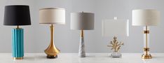 four different colored lamps sitting on top of a white marble table next to each other