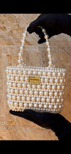 a hand holding a bag made out of pearls