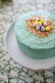 there is a cake with blue icing and eggs on top that has sprinkles