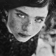 a woman with freckles on her face looking at the camera