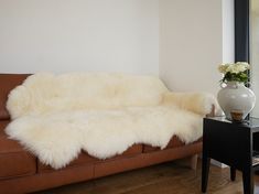 a living room with a couch, table and vase on the floor next to it