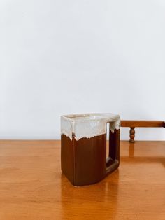 a brown and white mug sitting on top of a wooden table