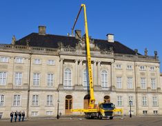 a yellow crane is being used to lift a large building