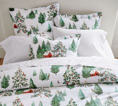 a bed covered in white sheets and pillows with christmas trees printed on the comforter