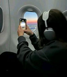 a woman is taking a photo with her cell phone while flying in an airplane over the city