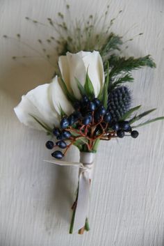 a boutonniere with blue berries and white flowers