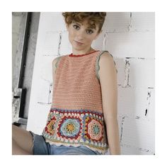 a woman is sitting on the floor wearing shorts and a crocheted top with an open back