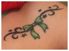 a woman's back with a green bow tattoo