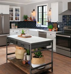 a kitchen with an island in the middle and potted plants on the counter top