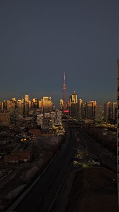 the city skyline is lit up at night, with tall buildings in the distance and cars driving on the road