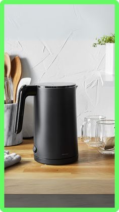 a black kettle sitting on top of a wooden counter next to glass bowls and utensils