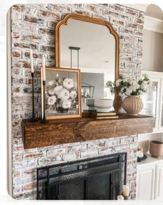 a fireplace with a mirror and vases on it in front of a brick wall