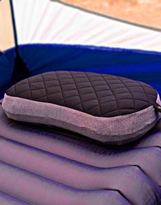 an inflatable bed with a pillow on top of it and a tent behind it