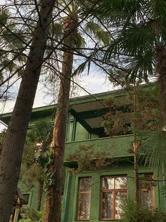 a green building with lots of trees in front of it