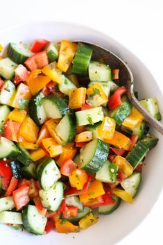 a white bowl filled with cucumber and tomato salad on top of a table