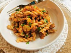 a white plate topped with pasta and meat