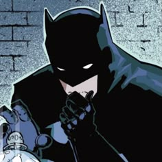 the batman is standing in front of a brick wall with his hands on his chest