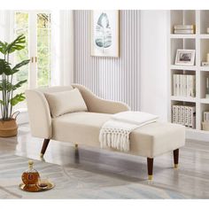 a white chaise lounger sitting on top of a hard wood floor next to a potted plant