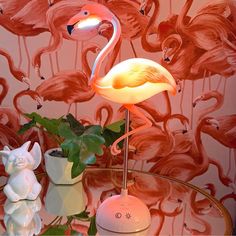 two flamingos are standing next to each other in front of a pink wallpaper