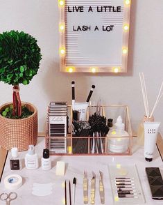 a table topped with lots of makeup and other items next to a sign that says live a little, lashes a lot