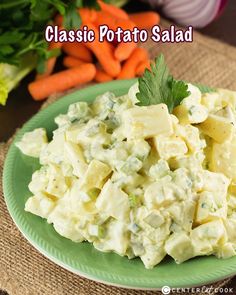 a green plate topped with potato salad next to carrots