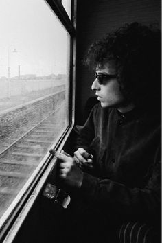 black and white photograph of a man looking out a train window at the railroad tracks