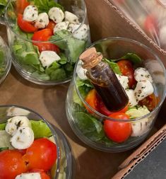 four bowls filled with salad and dressing on top of a table