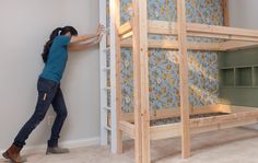 a woman standing next to a bunk bed in a room with blue and yellow wallpaper