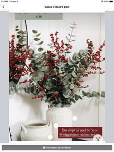 a white vase filled with red berries and greenery