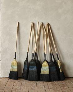 five brooms lined up against a wall