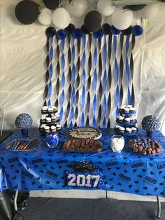 a blue table topped with lots of desserts and balloons