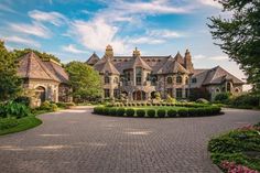 a large brick driveway leading to a house with lots of trees and bushes around it