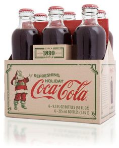 six bottles of coca - cola in a cardboard box with santa clause on the front