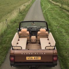 the back end of a brown and tan truck parked on top of a dirt road