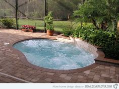 a hot tub in the middle of a patio surrounded by plants and flowers on either side