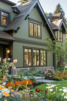 a green house with lots of flowers in the front yard