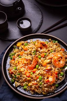 a plate full of rice and shrimp with chopsticks next to it on a table