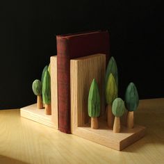 a wooden bookend with trees on it sitting on a table next to a book