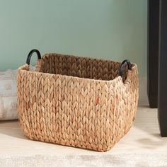 a woven basket sitting on top of a wooden floor next to a white and black pillow