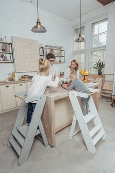 two children and an adult are sitting at a kitchen table with ladders in front of them