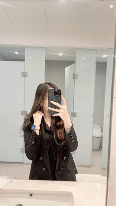 a woman taking a selfie in front of a bathroom mirror with her cell phone